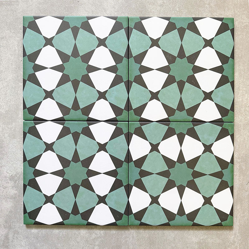 Four Agadir Verde Moroccan-style 20x20cm porcelain tiles laid together, forming a continuous geometric star pattern in soft green, white and charcoal tones.