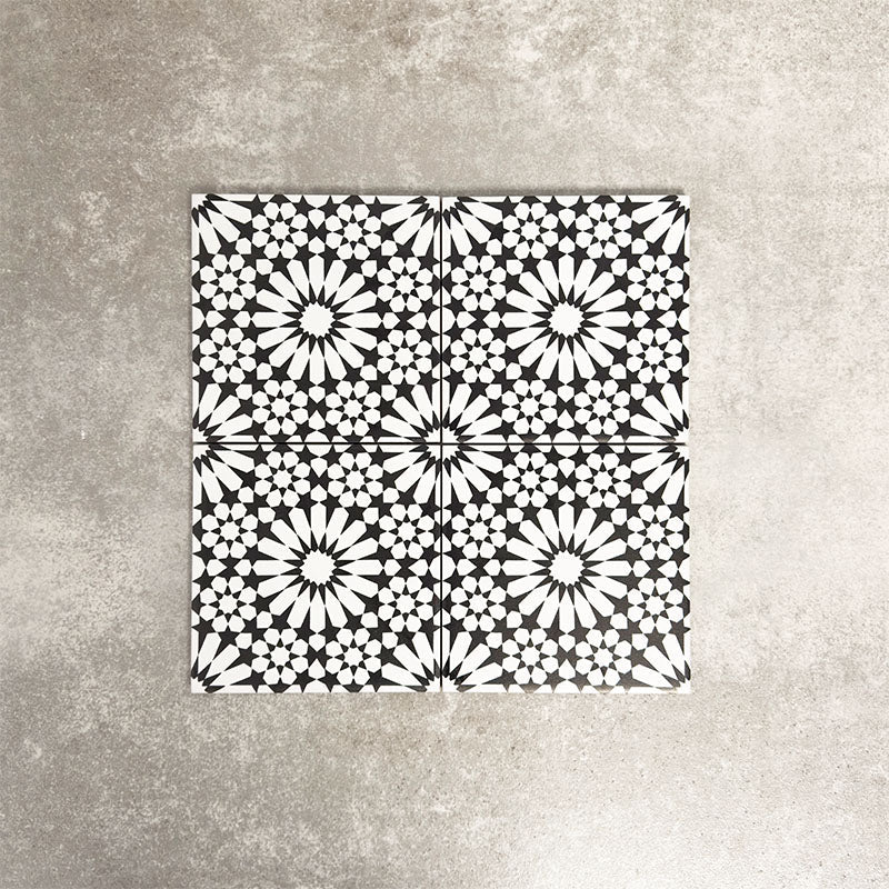 Fez Mini Winter Moroccan-style porcelain tile, featuring an intricate black and white geometric star pattern inspired by traditional Moroccan design. The 15 × 15cm square format highlights the fine encaustic-effect detailing and strong contrast, making it ideal for creating striking feature walls, splashbacks, or patterned floors in both contemporary and classic interiors.