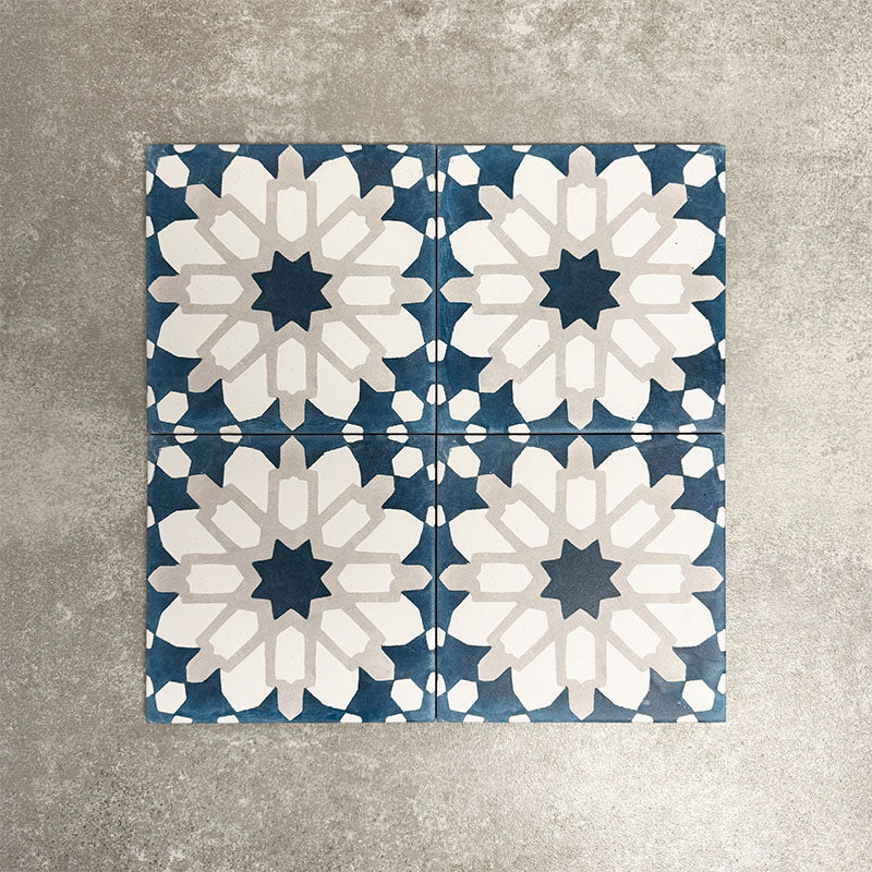 Souk Blue D 20×20cm Moroccan-style porcelain tiles arranged in a blue, white and grey geometric pattern.