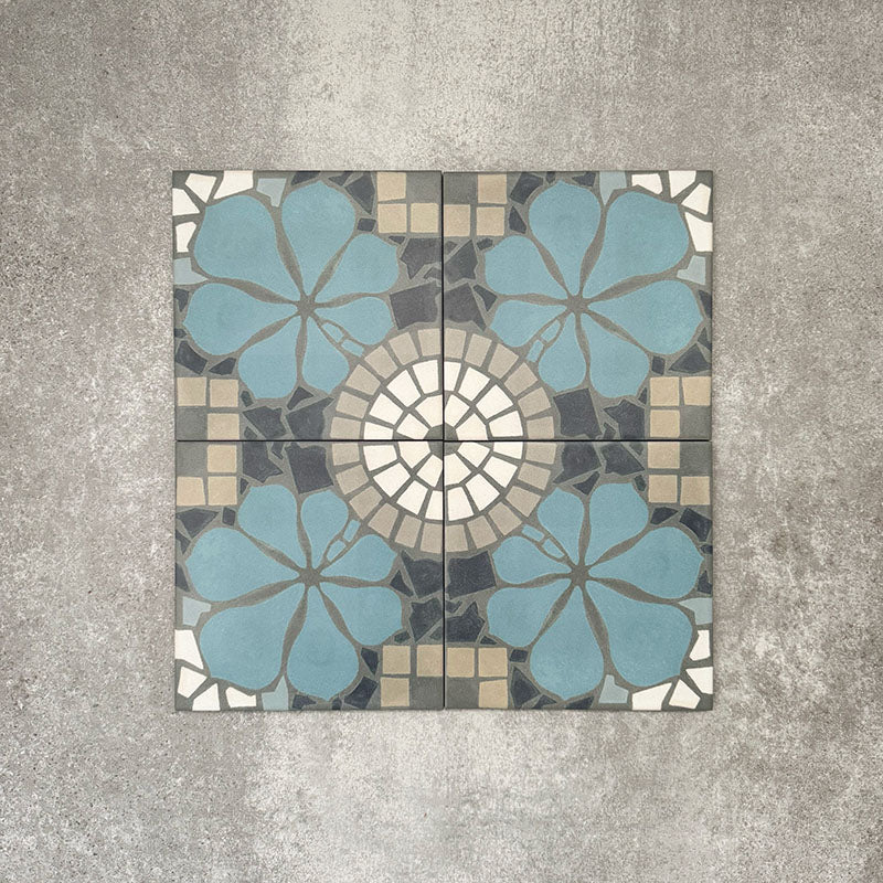 Four Nantes Azul Blue Moroccan-style tiles arranged to show the full pattern repeat. The 20x20cm tiles combine soft blue floral motifs with a central circular mosaic detail in cream, grey and stone tones, forming a symmetrical, traditional Moroccan-inspired design suitable for floors and walls.
