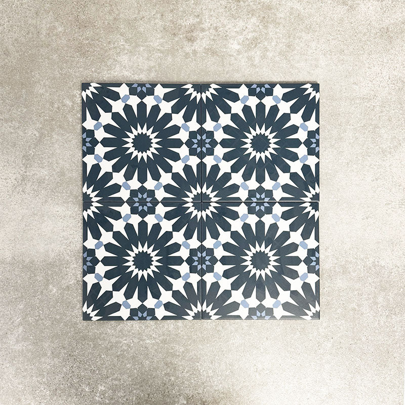 Fez Federal Blue 20x20cm Moroccan-style porcelain tile displayed against a textured grey background, highlighting the bold blue and white geometric star pattern with subtle pale blue detailing.