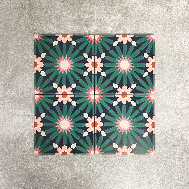 Fez Festival 20x20cm Moroccan-style porcelain tile displayed against a textured grey background, highlighting the bold multicolour geometric star pattern in deep teal, pink and warm neutral tones.