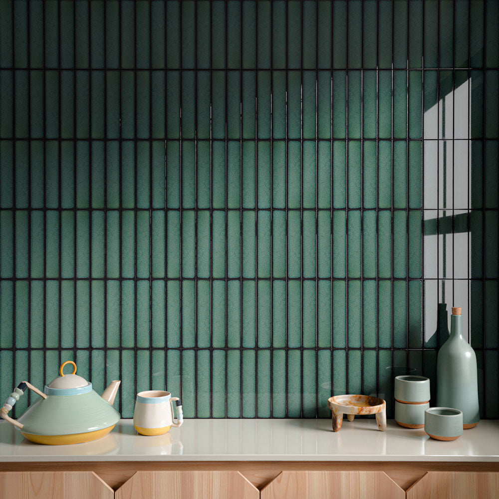 Interior wall featuring Alchemy Hunter Green 6.5cm x 30cm tiles laid vertically, showcasing rich green tones and subtle surface variation, styled with decorative ceramics and a light wood cabinet.