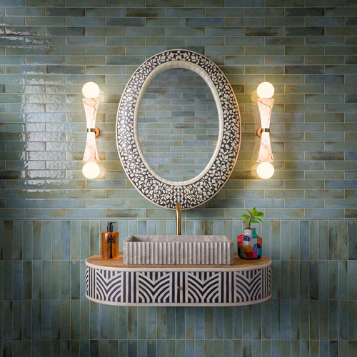 Bathroom featuring Allegra Celadon Green gloss brick tiles, combining soft green and blue-toned marble-effect variation with a reflective glazed finish. Installed in both horizontal and vertical layouts, the tiles create subtle contrast and visual interest, while the decorative vanity, statement mirror and warm brass accents bring a sophisticated Mediterranean-inspired character to the space.