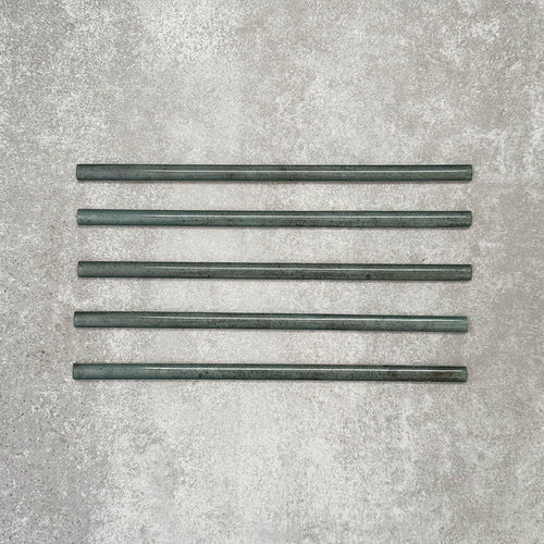 Allegra Green Gloss pencil bullnose border tiles in a 1.2 × 30cm ceramic format, shown as five pieces laid horizontally to display the slim profile, rounded edges, tonal green variation and glossy glazed finish on a neutral textured background.