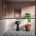 Bathroom featuring Almeira Giza Moroccan style wall and floor tiles in 20cm x 20cm, showcasing a grey and white geometric patterned floor, white brick wall tiles with a black marble border, blush pink walls, a black fluted marble pedestal basin and terracotta planter for a contemporary Moroccan-inspired interior.