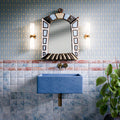 Bathroom featuring Amalfi Square Azul Vintage Marble 11x11cm wall tiles with rich blue marble-effect variation, paired with a matching blue basin, decorative border detail, brass fittings and patterned wallpaper. The combination creates a bold, characterful space with a vintage-inspired Mediterranean feel.