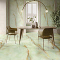 Dining room featuring Anastasia Jade Green Onyx Matt 60 × 120cm stone effect floor and wall tiles, with soft green tones and flowing gold veining, paired with a wooden table, upholstered chairs, and statement lighting.