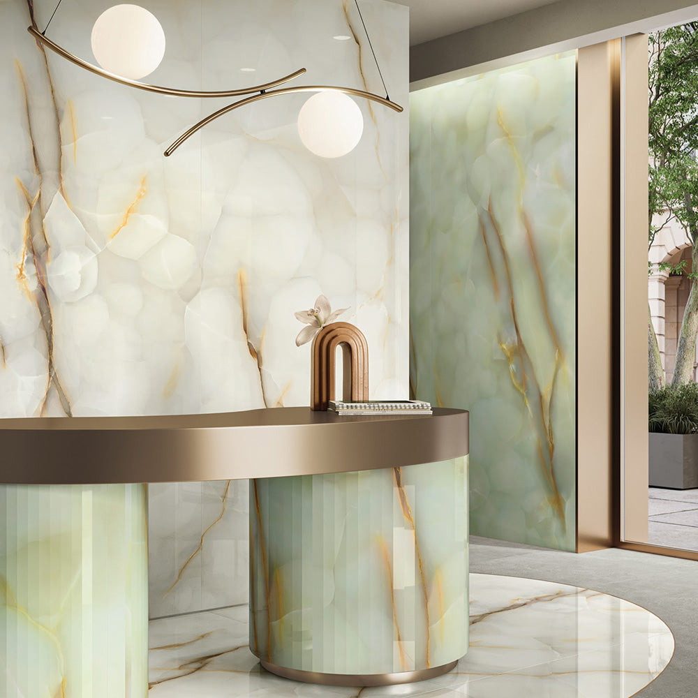 Interior reception space featuring Anastasia Jade Green Onyx Polished 60 × 120cm stone effect wall and floor tiles, with soft green tones and flowing gold veining, paired with a curved desk, warm metallic accents, and soft ambient lighting.