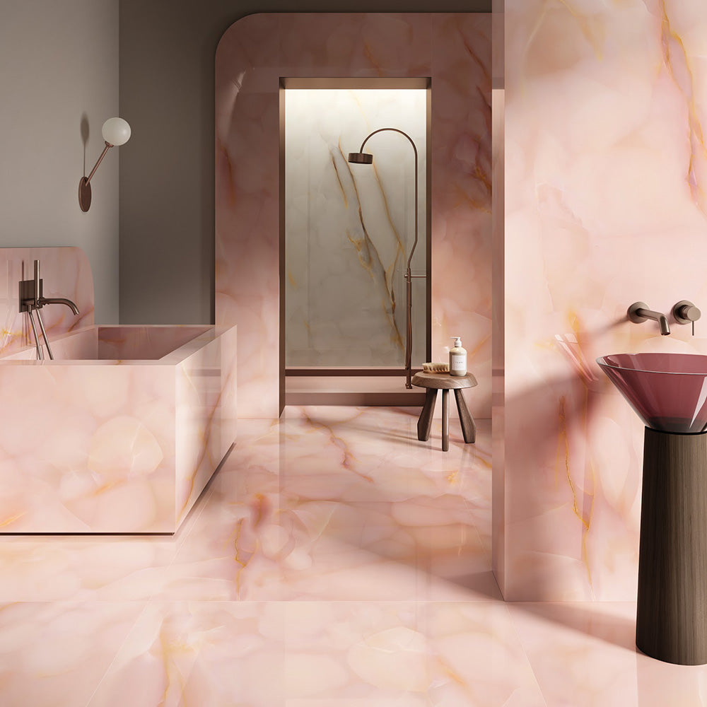 Bathroom interior featuring Anastasia Rose Onyx Matt 60 × 120cm stone effect wall and floor tiles, with soft pink tones and delicate gold veining, paired with a freestanding bath, walk-in shower, and warm brass fittings.