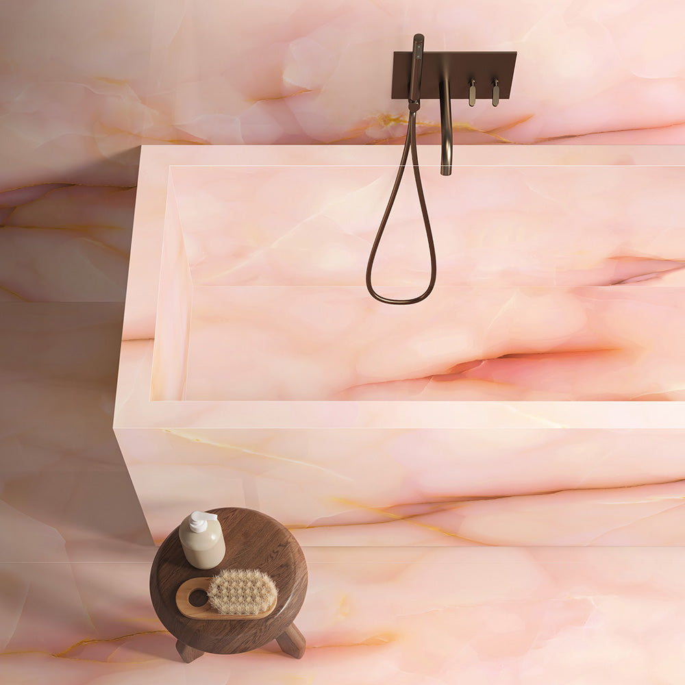 Bathroom interior featuring Anastasia Rose Onyx Matt 60 × 120cm stone effect wall and floor tiles, with soft pink tones and delicate gold veining, paired with a freestanding bath, walk-in shower, and warm brass fittings.