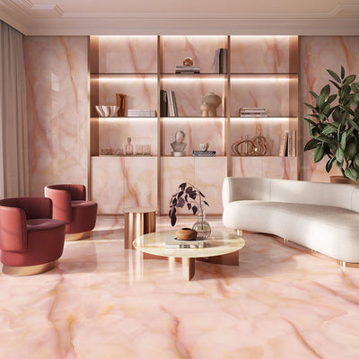 Living room featuring Anastasia Rose Onyx Polished 60 × 120cm stone effect floor and wall tiles, with soft pink tones and delicate gold veining, paired with curved seating, warm lighting, and built-in shelving.