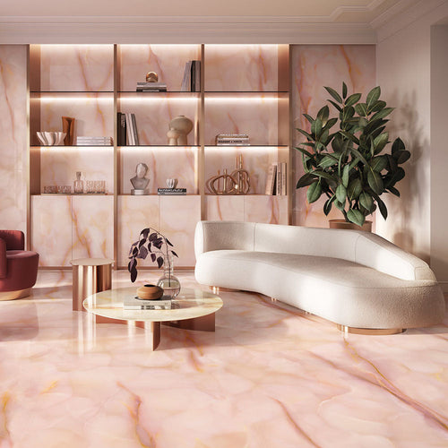 Living room featuring Anastasia Rose Onyx Polished 60 × 120cm stone effect floor and wall tiles, with soft pink tones and delicate gold veining, paired with curved seating, warm lighting, and built-in shelving.