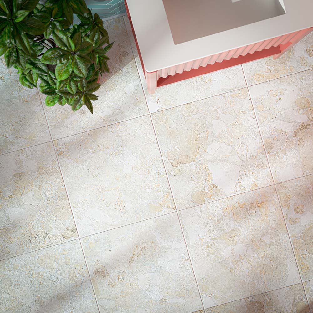 Contemporary bathroom featuring Baresi Puro 3D terrazzo effect porcelain floor tiles, paired with aquamarine glossy herringbone wall tiles, blush pink limewashed walls, a coral fluted vanity, brushed brass fittings and indoor planting for a vibrant, design-led interior.