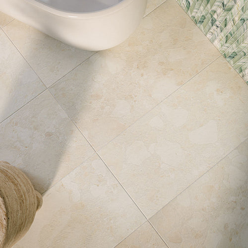 Bathroom featuring Baresi Puro Light 3D 60x120cm terrazzo-effect porcelain wall and floor tiles in warm beige tones, styled with green textured feature tiles, a freestanding bath, brass fixtures, and bohemian-inspired décor.