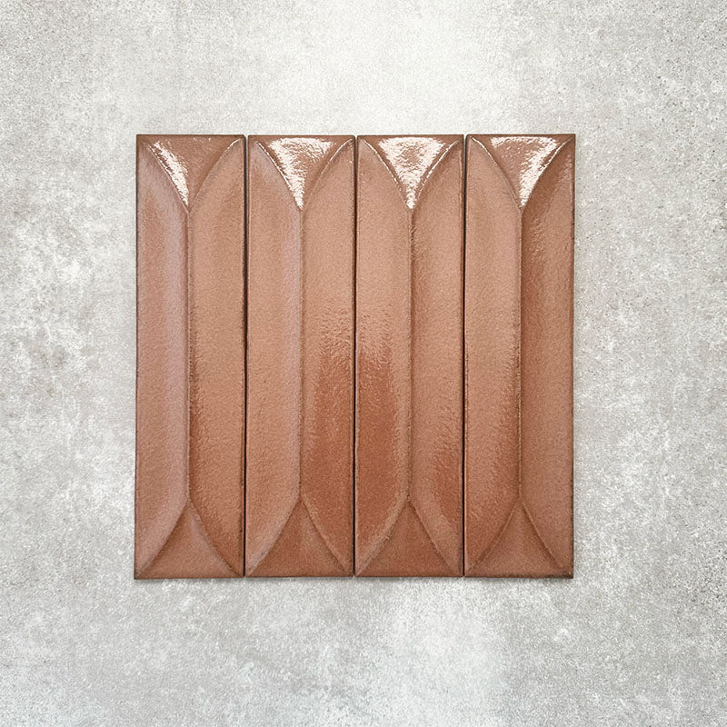 Baroque Decor Cotto porcelain wall tile in a 9.1cm x 37.5cm format, featuring a warm terracotta metallic finish with a raised geometric relief design and gently distressed edges, displayed against a textured concrete-effect background.