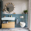 Bathroom featuring Baroque Laguna Blue 9.1cm x 37.5cm porcelain wall tiles, laid vertically around a basin and toilet, paired with white gloss tiles, marble effect flooring and a wooden vanity.