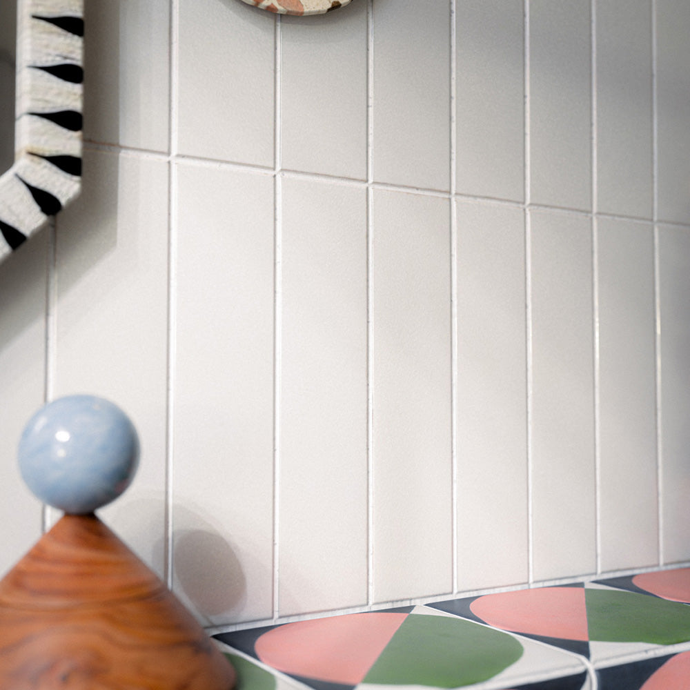 Bathroom featuring Baroque Vanilla 9.1x37.5cm porcelain wall tiles, paired with bold geometric patterned wall and floor tiles, terrazzo-effect basin, and eclectic décor for a playful contemporary interior.