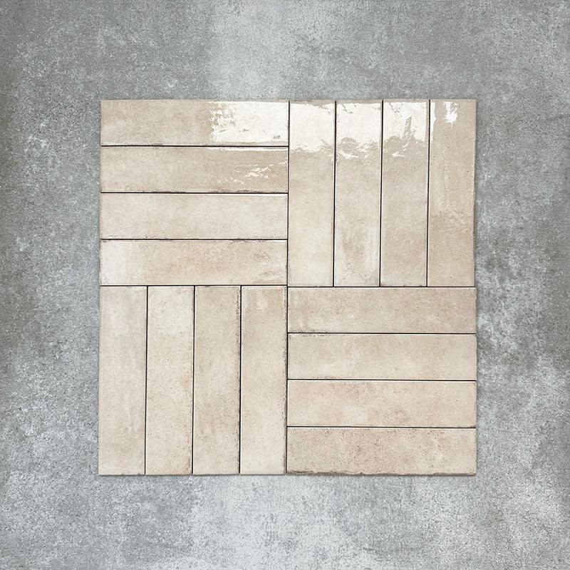 Nomad Oatmeal brick wall tiles in a 6 × 24.6cm format, shown laid together in a basketweave layout to highlight the warm neutral tone, gloss finish and subtle surface variation.