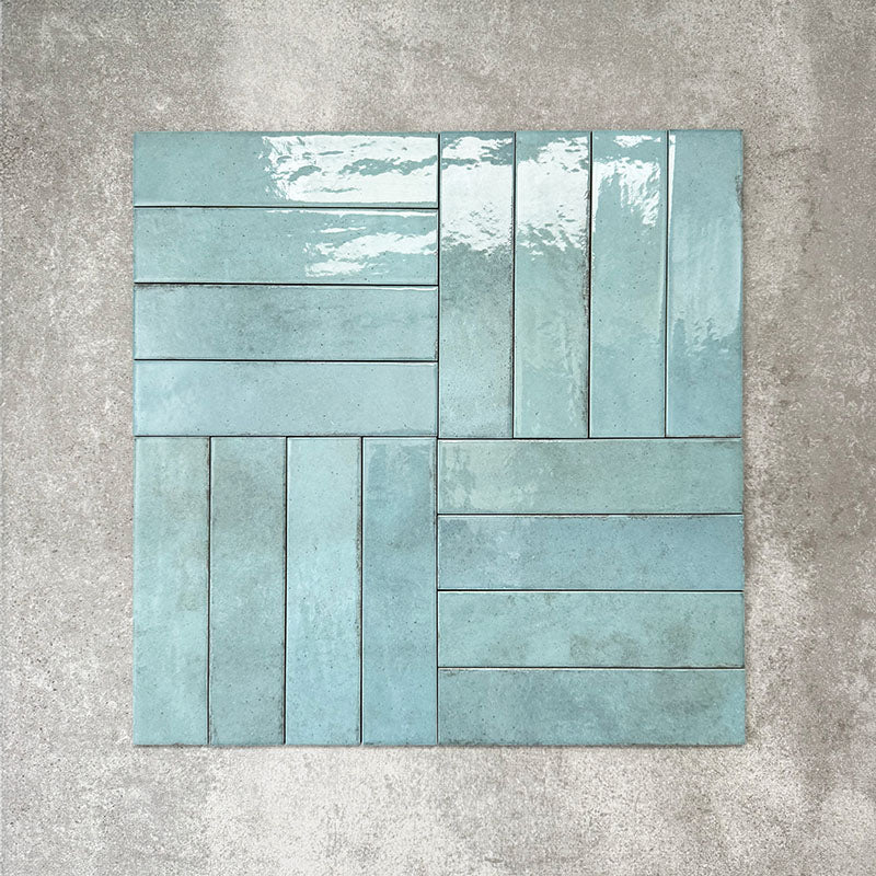 Nomad Aquamarine brick wall tiles in a 6 × 24.6cm format, shown laid in a basketweave layout with a glossy, lightly textured surface and soft blue-green tones, creating an industrial-style look.