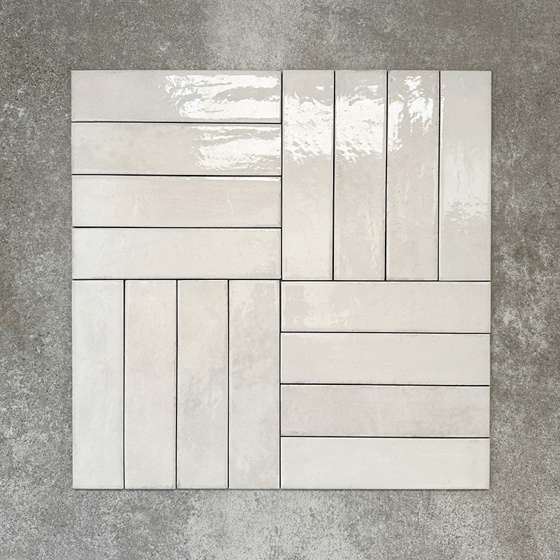 Nomad White brick wall tiles in a 6 × 24.6cm format, shown laid together in a basketweave layout to highlight the soft white colour, gloss finish and subtle surface variation.