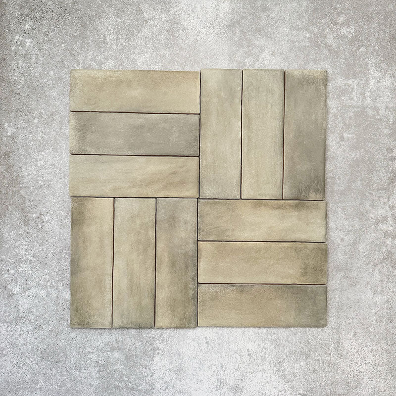 Flat lay of Zellige Weald Green 6.5×20cm Moroccan-style ceramic brick tiles, shown in a basketweave layout, highlighting soft green and earthy tonal variation, irregular edges and a handmade-look glazed finish on a neutral background.