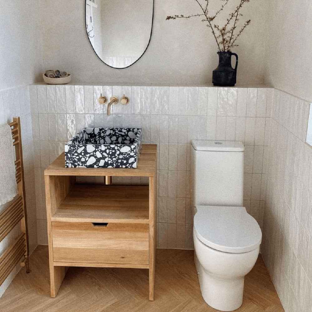 Bathroom featuring Zellige Oyster Brick Moroccan-style ceramic wall tiles in a 6.5 × 20cm brick format, installed vertically to create textured half-height walls, paired with a terrazzo countertop basin, warm wood vanity and brass fixtures for a soft, contemporary bathroom design.