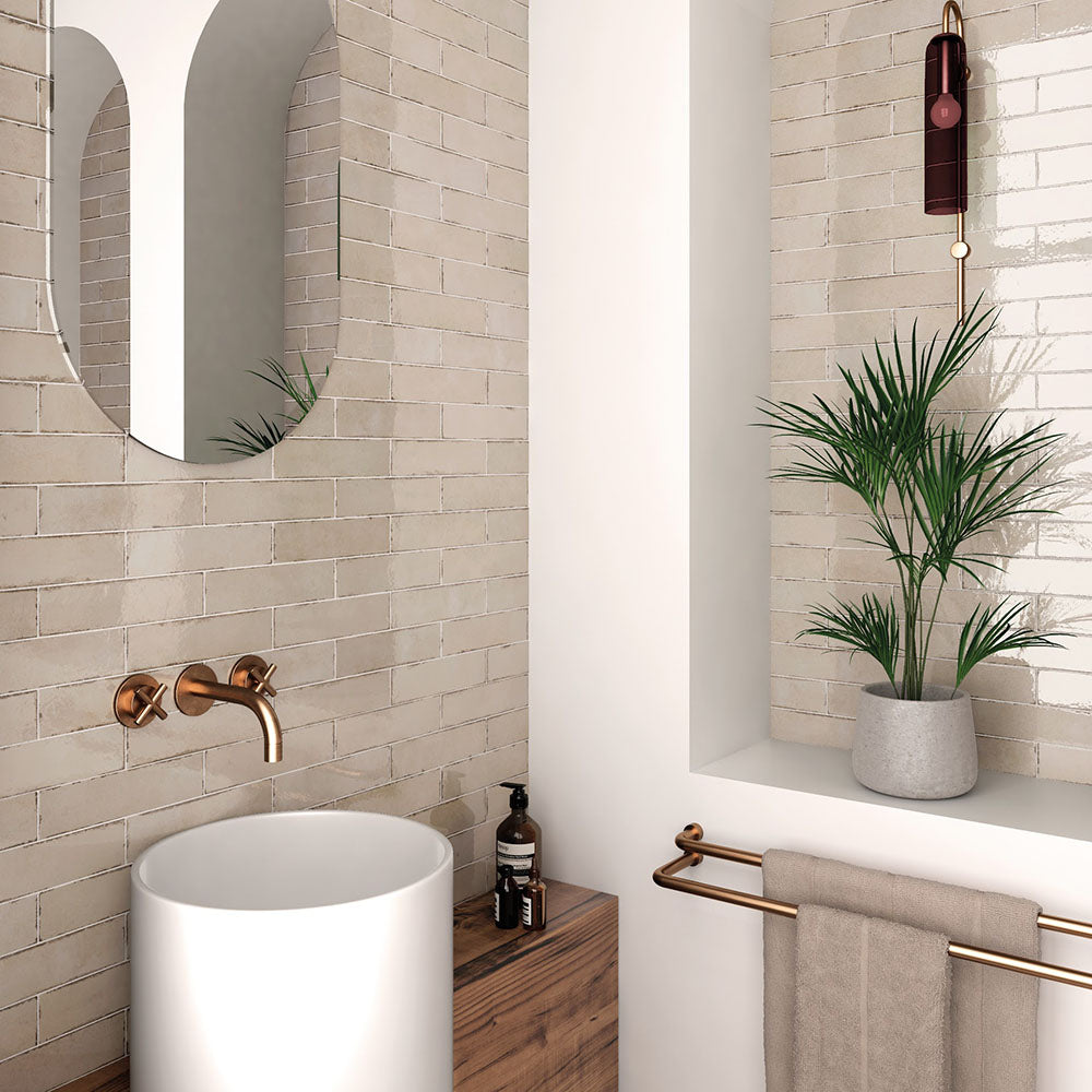 Bathroom featuring Nomad Oatmeal brick wall tiles in a 6 × 24.6cm format, laid horizontally behind a countertop basin for a warm, industrial-inspired finish.