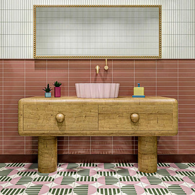 Bathroom interior featuring Abstract Serit Patterned Tiles in a 20x20cm format, laid as a bold geometric floor design. The repeating pattern combines soft pink, deep green and crisp white tones with striped detailing, paired with a wooden vanity unit and blush basin to create a playful yet contemporary bathroom setting.