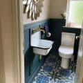 Bathroom interior featuring London Streets Baker Street 20x20cm Victorian Moroccan style floor tiles, styled with deep blue wall panelling, brass fittings and a compact wall-mounted sink, creating a bold patterned bathroom floor.