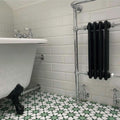 Bathroom setting featuring Agadir Green Moroccan-style 20x20cm porcelain floor tiles, showcasing a geometric star pattern in green and white, styled with a freestanding bath, white wall tiles and chrome fittings.