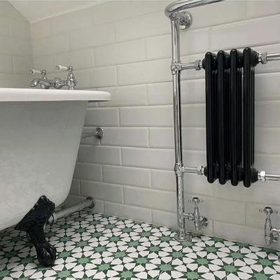 Bathroom setting featuring Agadir Green Moroccan-style 20x20cm porcelain floor tiles, showcasing a geometric star pattern in green and white, styled with a freestanding bath, white wall tiles and chrome fittings.