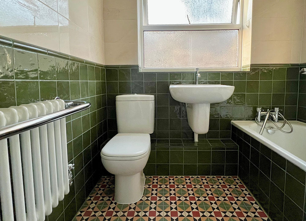Bathroom setting featuring Newton MINI Manor Victorian style 15x15cm floor tiles in a geometric pattern, paired with Zellige Botanical Green 13.2x13.2cm Moroccan-style wall tiles, styled with a classic suite and vintage-inspired fittings.