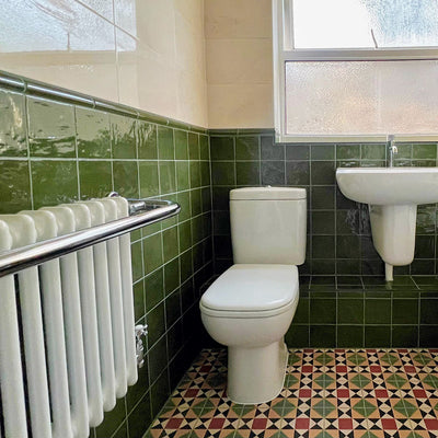 Bathroom setting featuring Newton MINI Manor Victorian style 15x15cm floor tiles in a geometric pattern, paired with Zellige Botanical Green 13.2x13.2cm Moroccan-style wall tiles, styled with a classic suite and vintage-inspired fittings.
