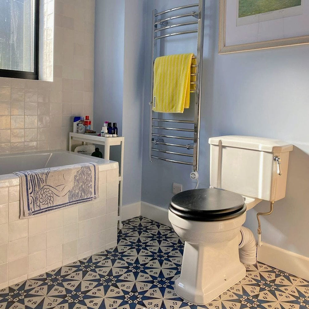 Bathroom featuring Zellige Oyster Square Moroccan-style ceramic tiles in a 10 × 10cm format, installed in a neat grid around the bathtub, with a glossy oyster-white glaze, softly uneven surfaces and subtle tonal variation creating a handcrafted backdrop that contrasts beautifully with the patterned floor tiles and classic bathroom fittings.