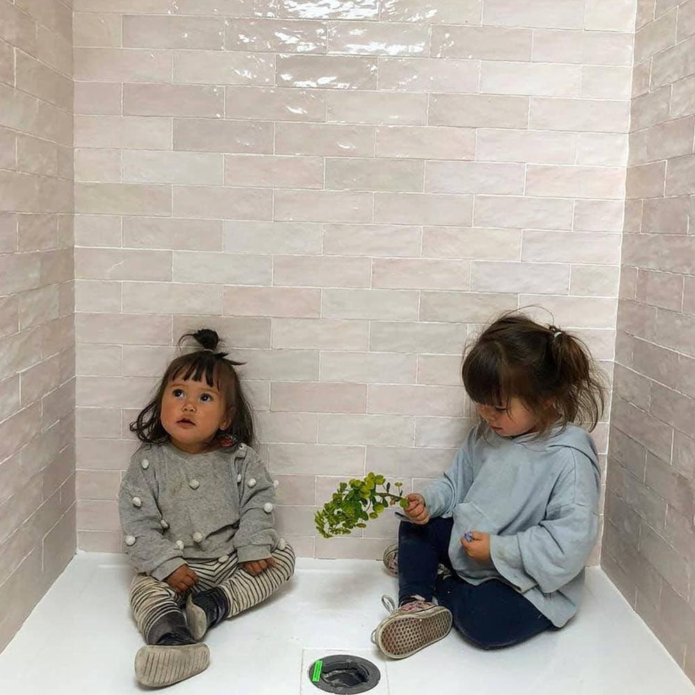 Bathroom shower area featuring Zellige Pink Mist Brick 6.5 × 20cm Moroccan-style ceramic wall tiles in soft pale pink tones, laid in a horizontal brick layout with a glossy finish, creating a light, calming and handcrafted zellige-effect backdrop.
