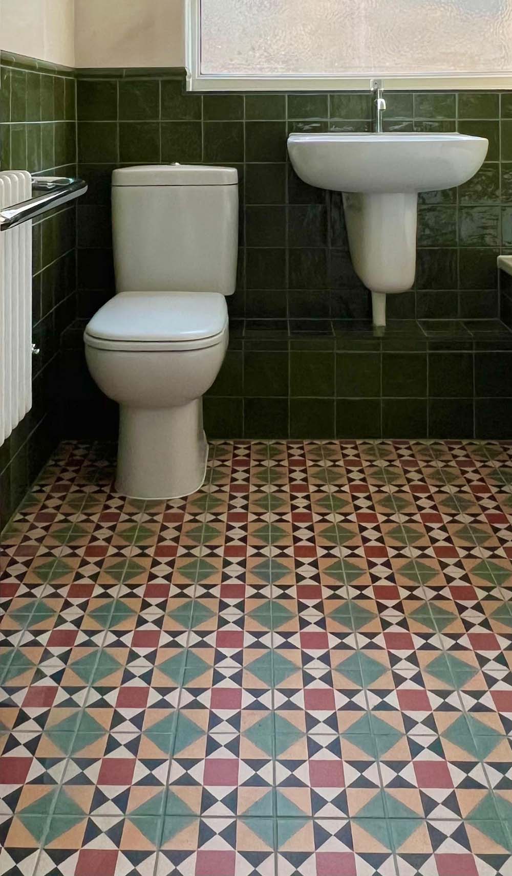 Bathroom setting featuring Newton MINI Manor Victorian style 15x15cm floor tiles in a geometric pattern, paired with Zellige Botanical Green 13.2x13.2cm Moroccan-style wall tiles, styled with a classic suite and vintage-inspired fittings.