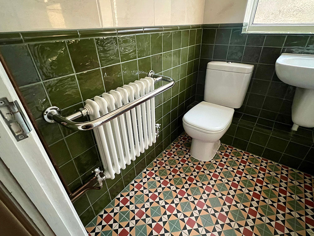 Bathroom setting featuring Newton MINI Manor Victorian style 15x15cm floor tiles in a geometric pattern, paired with Zellige Botanical Green 13.2x13.2cm Moroccan-style wall tiles, styled with a classic suite and vintage-inspired fittings.