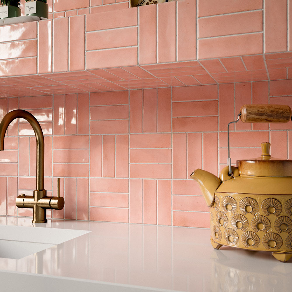 Kitchen featuring Benomar Pink Gloss 5x15cm Moroccan-style wall tiles in a geometric layout, styled with pastel blue cabinetry, brass fixtures, and decorative accents for a playful contemporary interior.
