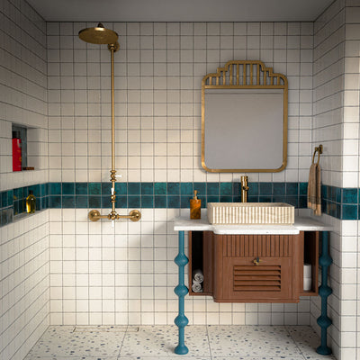 Bathroom featuring Bora Bora White Sand Square wall tiles in a 10cm x 10cm format with a flux glaze finish, paired with a teal feature border, brass shower fittings, terrazzo effect flooring and a floating timber vanity.