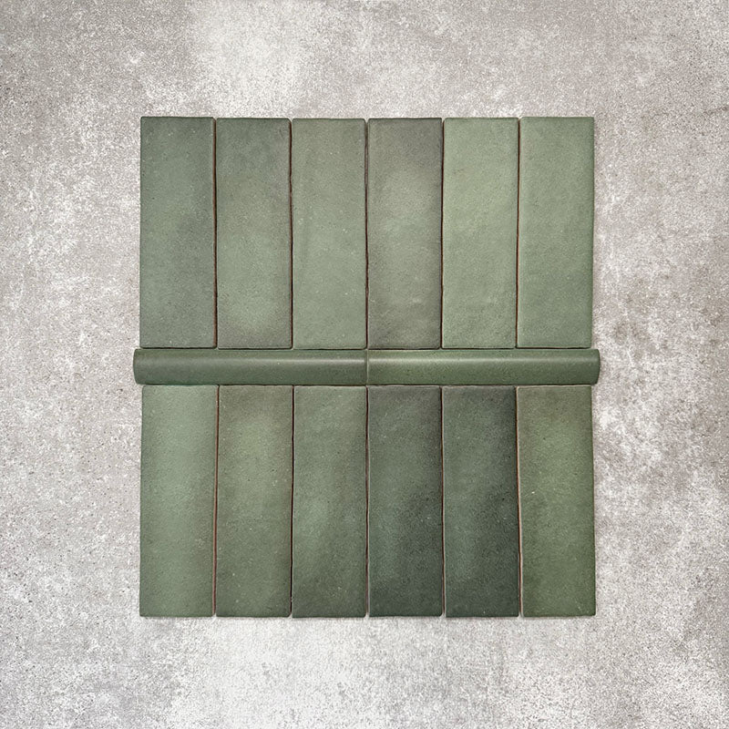 Flat lay of Zellige Malachite Green Moroccan-style ceramic tiles, showing 6.5×20cm brick tiles paired with a 3×20cm bullnose trim, highlighting the rounded edge detail, handmade-look texture and natural green tonal variation.