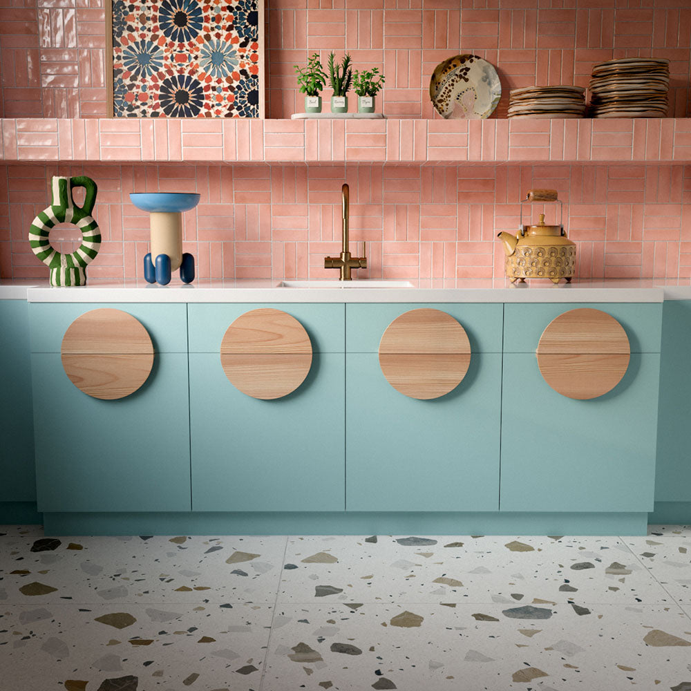 Kitchen featuring Byblos Cotton 60x120cm terrazzo-effect porcelain floor tiles, paired with blush pink Moroccan-style wall tiles, pastel blue cabinetry, and brass fixtures for a playful contemporary interior.