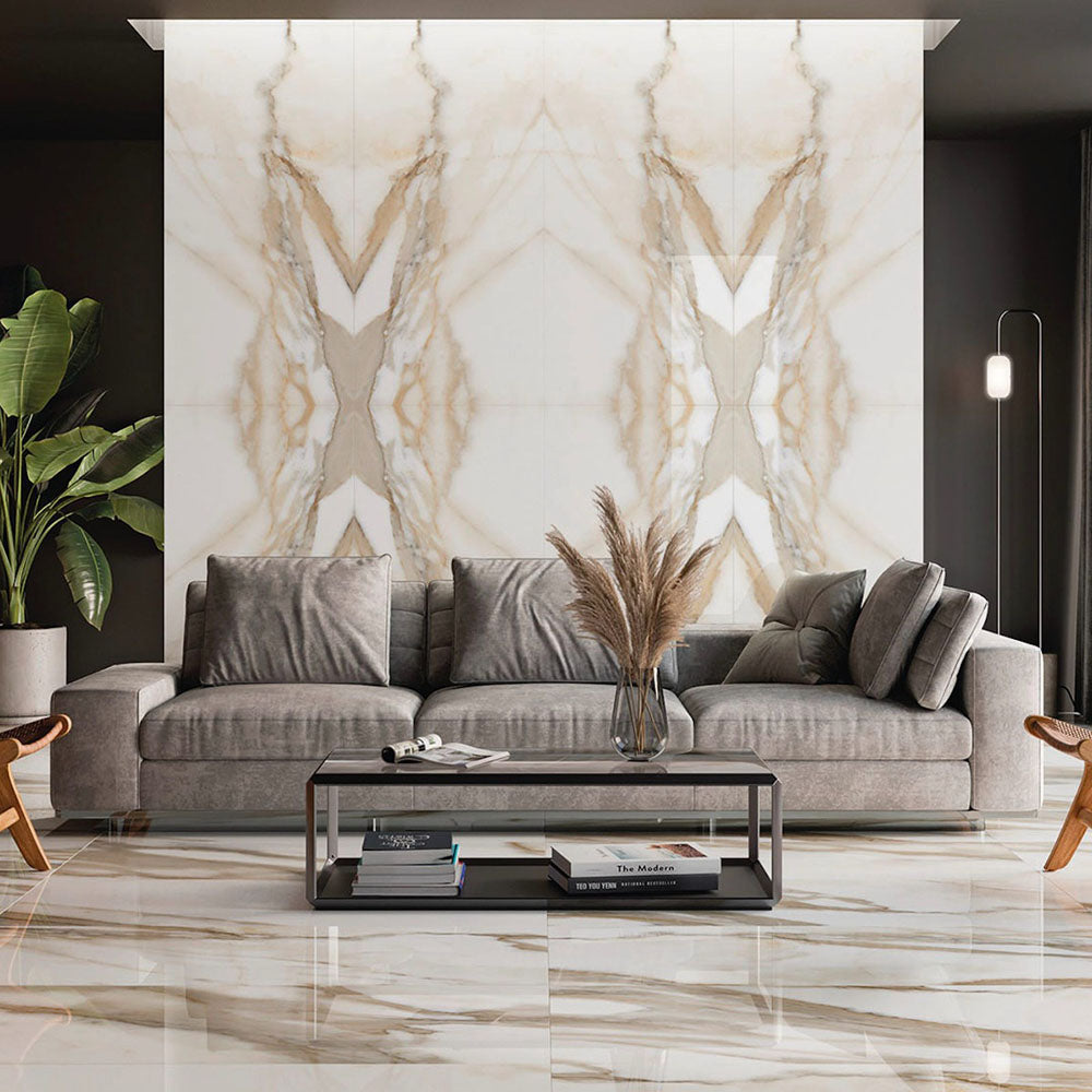 Living room featuring Calacatta Oro Marble Book Matched A & B 60 × 120cm porcelain wall and floor tiles, showcasing a striking mirrored veining layout with warm gold tones, paired with neutral furnishings for a refined, statement interior.