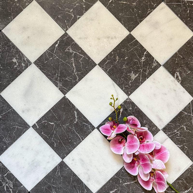 Chequerboard layout featuring Fayrouz Black 15.2x15.2cm natural marble tiles with a honed finish, paired with white marble tiles, installed diagonally and styled with pink orchid flowers for a soft decorative contrast.