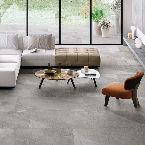 Living area featuring Comet Silver Stone 2cm 60 × 90cm porcelain tiles, showcasing soft silver-grey stone effect tones with subtle veining. Laid in a staggered pattern, the tiles create a calm, contemporary foundation, complemented by warm furnishings and natural light.