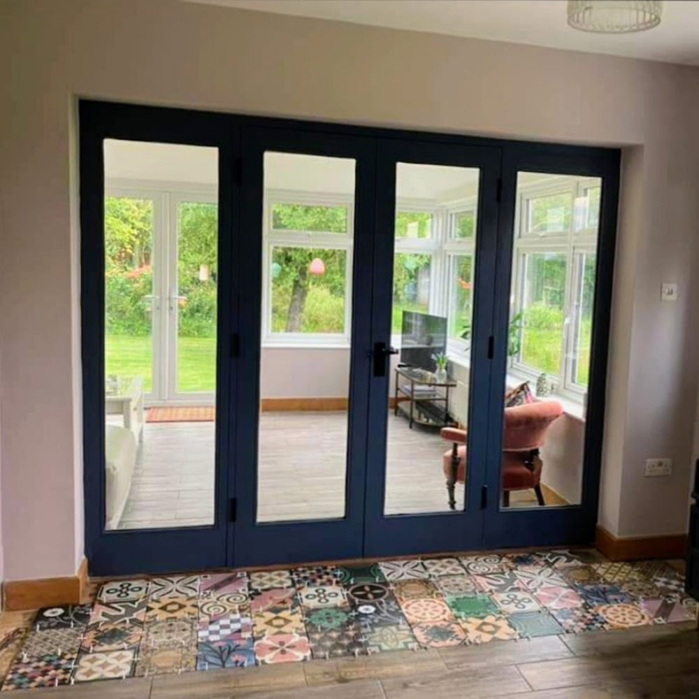 Doorway threshold featuring Cuba Patchwork Moroccan-style porcelain tiles in a 20×20cm square format, laid in a mixed patchwork design combining geometric and traditional motifs in earthy, green, blue and terracotta tones, creating a striking transition between indoor and outdoor spaces.