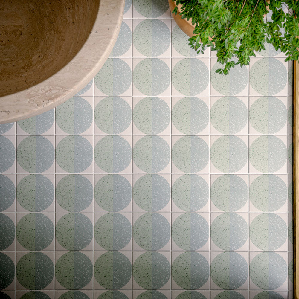 Bathroom featuring Eclipse Salvia 20x20cm terrazzo-effect patterned wall and floor tiles, styled with a freestanding stone bath, green marble-effect brick tiles, brushed brass fixtures and botanical-inspired contemporary décor