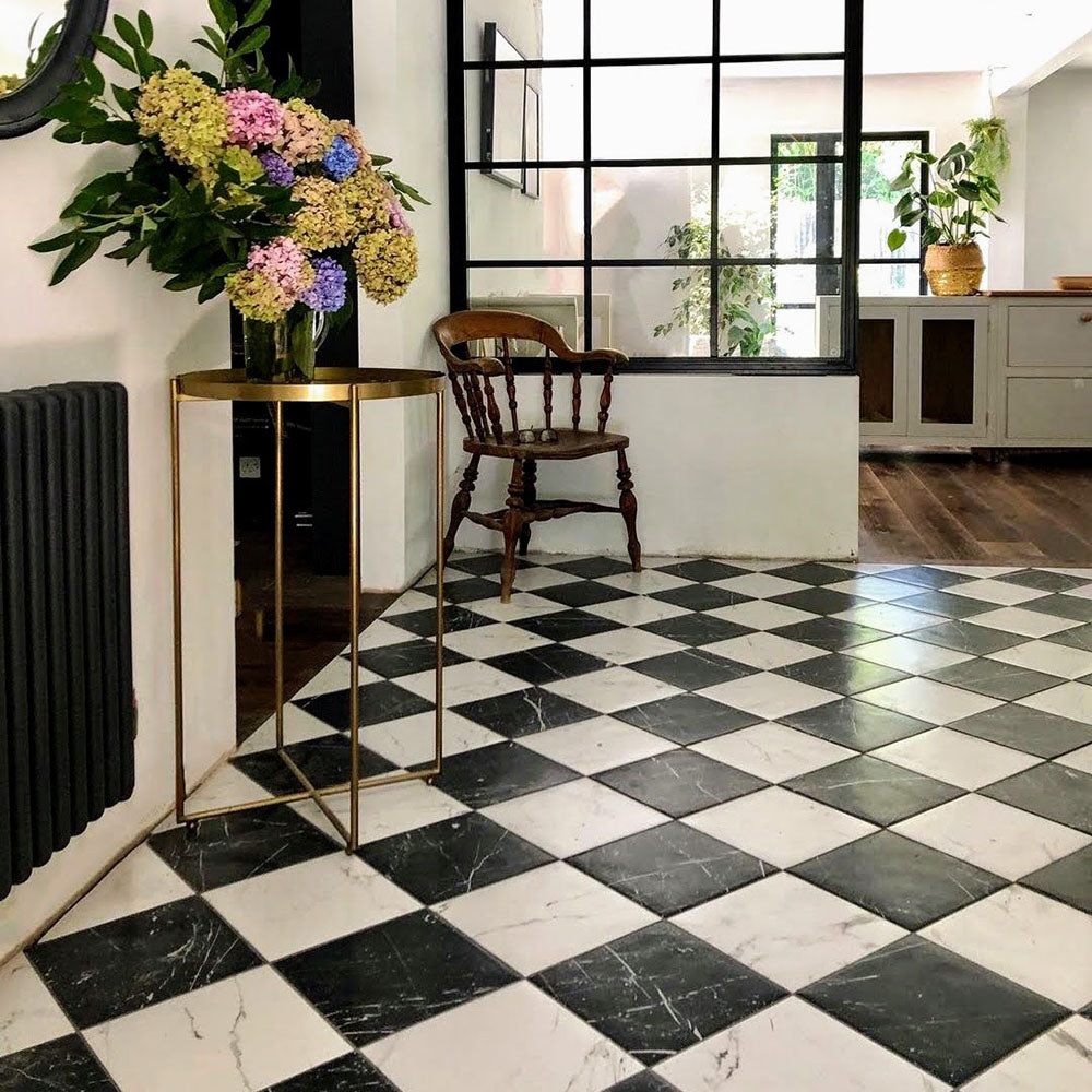 Entrance hallway featuring Florence Marquina Black 25x25cm marble-effect porcelain floor tiles, laid in a classic black and white checkerboard pattern and styled with industrial-style glazing, wooden furniture and soft neutral décor for a timeless, elegant look.