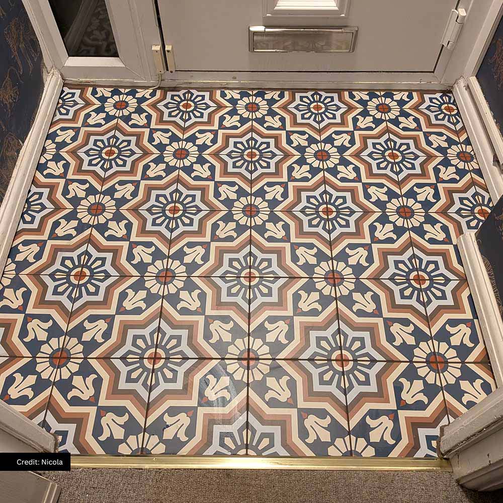 Entrance hallway featuring Balthazar Grand 20×20cm Moroccan-style porcelain floor tiles, laid in a repeating geometric pattern with deep blue, warm brown and cream tones, creating a striking and welcoming statement floor at the doorway.