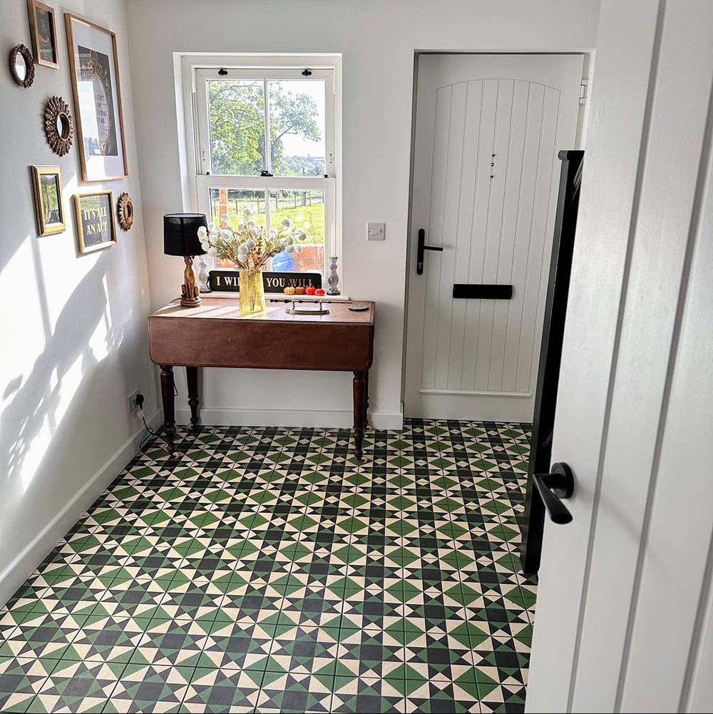 Bright hallway featuring Greenbrook Manor anti-slip encaustic Victorian-style porcelain floor tiles, laid in a classic green, black and cream geometric pattern, paired with white walls, a traditional console table and a painted timber front door.